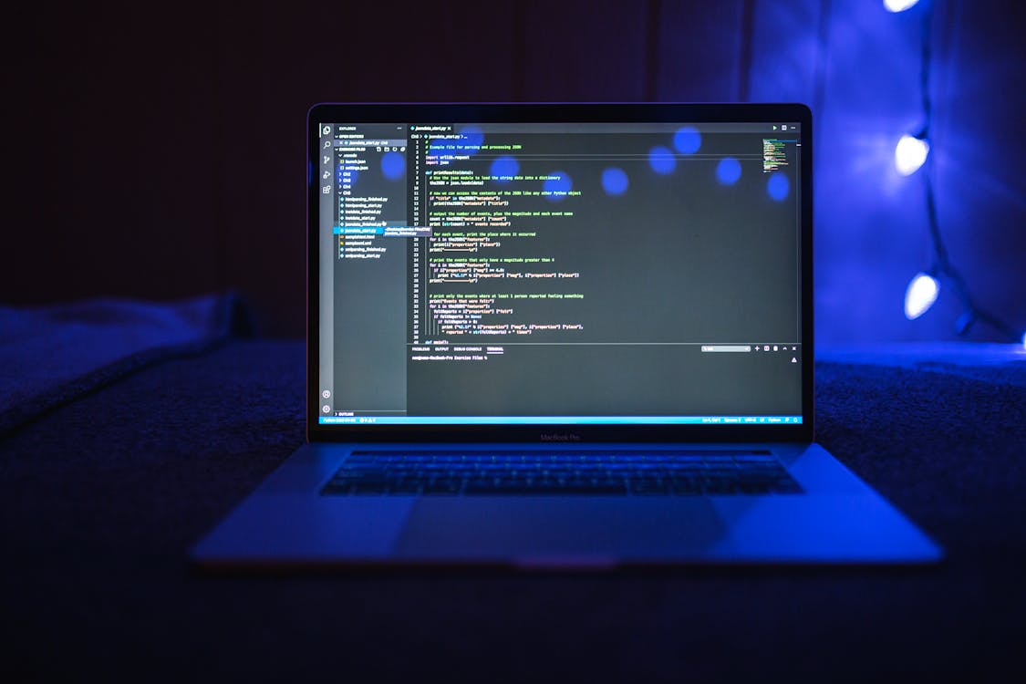 Laptop com código de programação na tela em ambiente com iluminação azul representando otimização técnica de performance